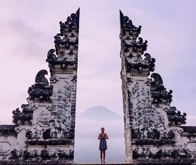 インドネシア・バリの遺跡で手を合わせる女性と背後に見える山