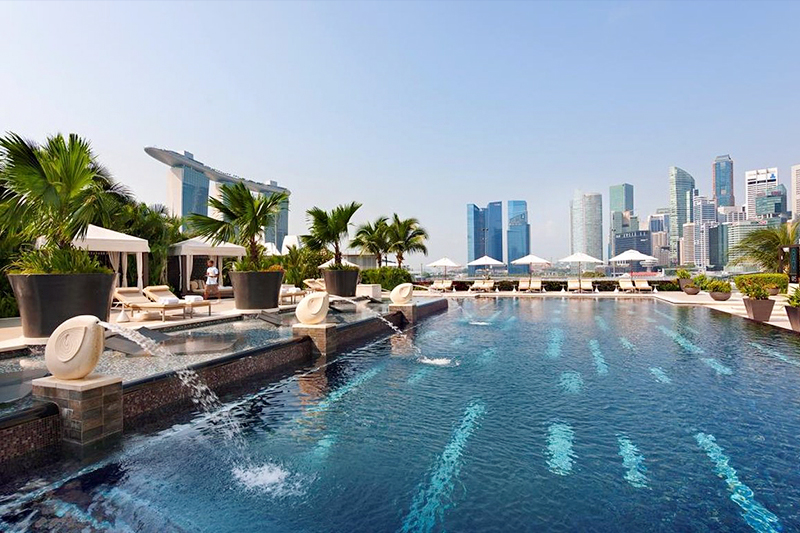ダウンタウンの高層ビル群を望むマンダリン オリエンタル シンガポールの屋外プール